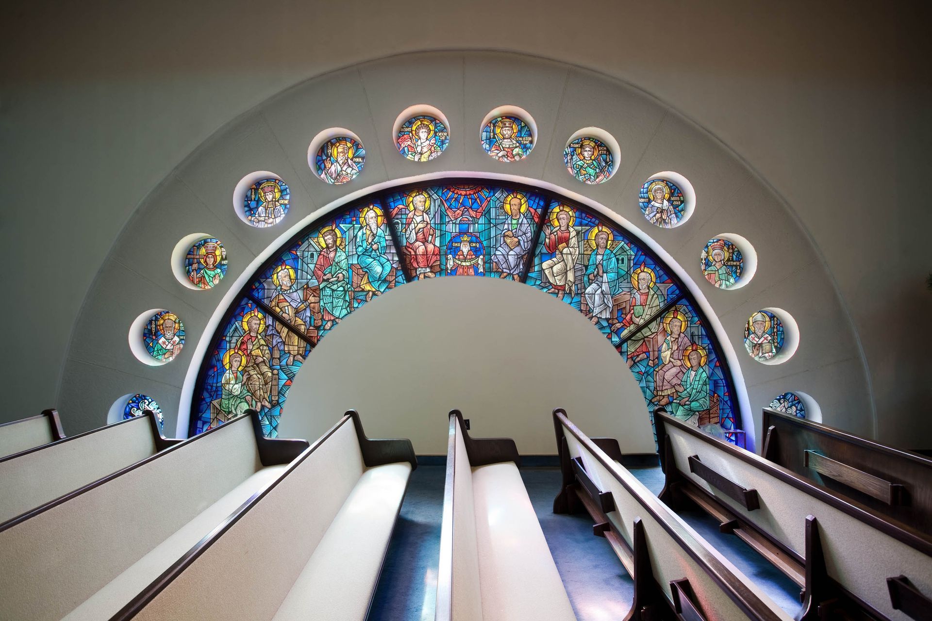 Church pews converging toward a broad stained-glass arch