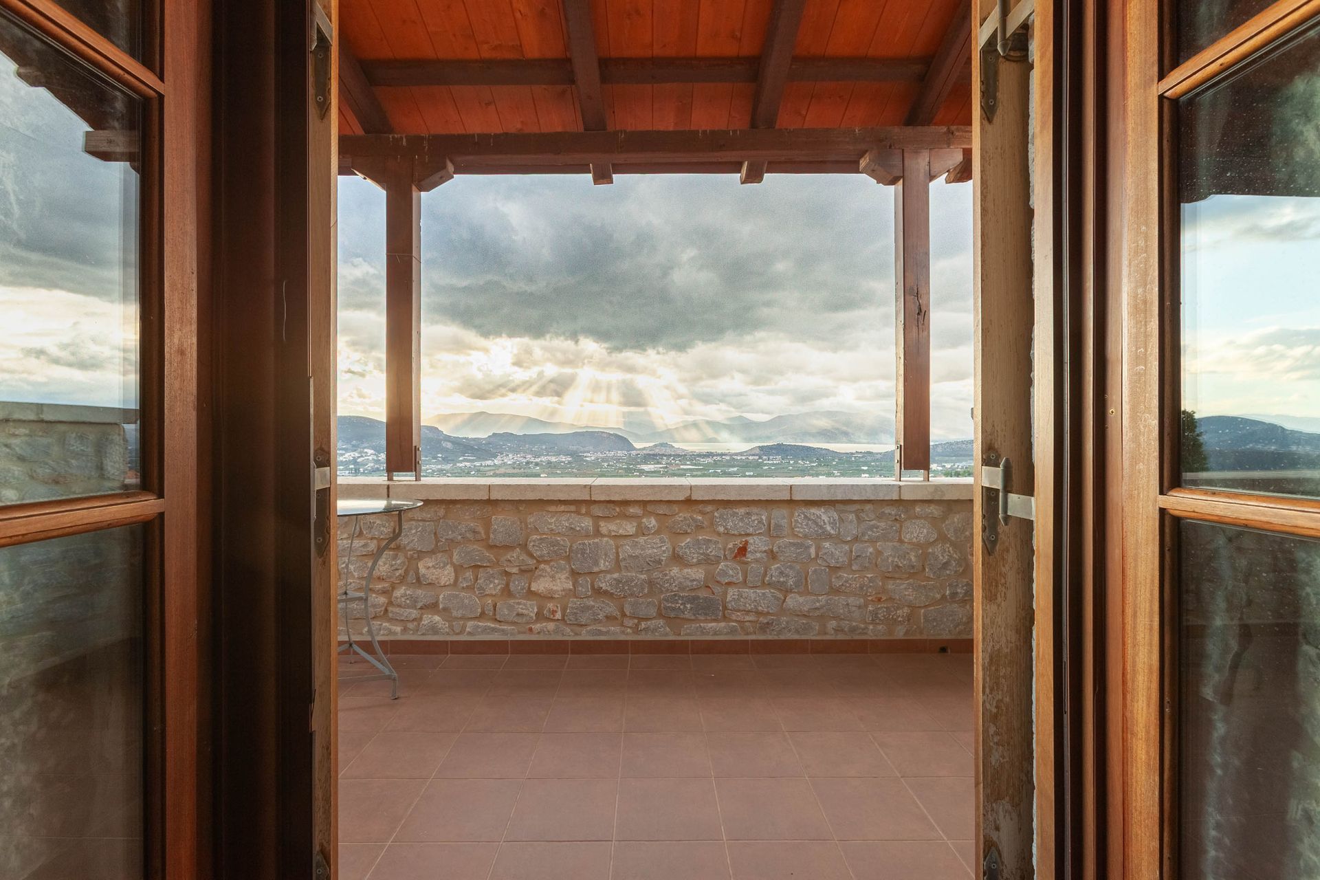 Wooden doorway framing sun rays over a coastal mountain landscape
