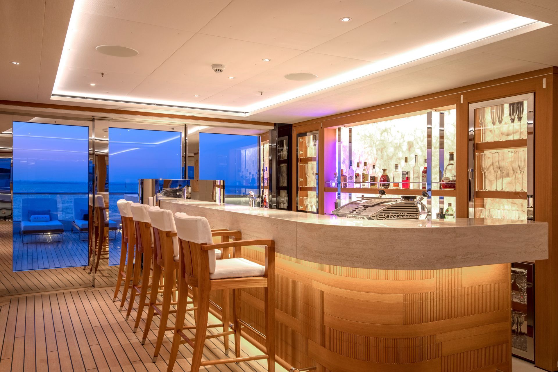 Curved sundeck bar aboard motor yacht Hasna at blue hour