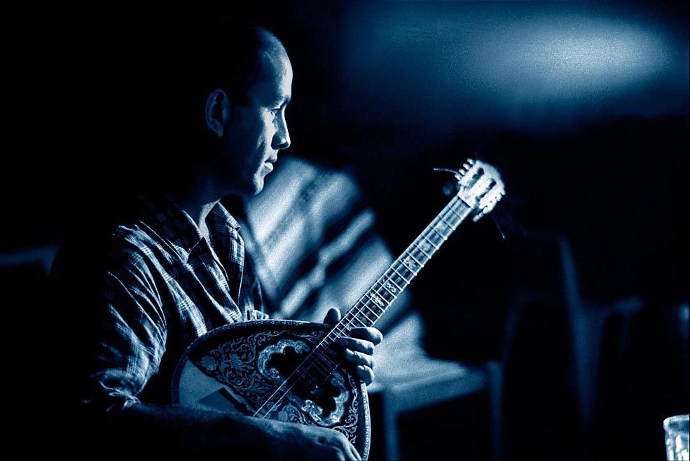 Musician playing bouzouki under blue light