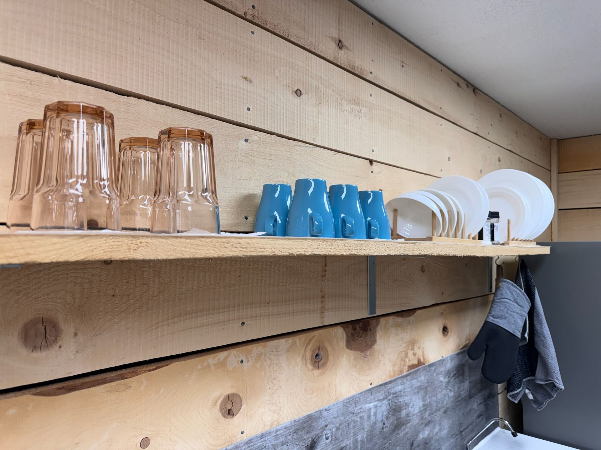 A wooden shelf with glasses and plates on it