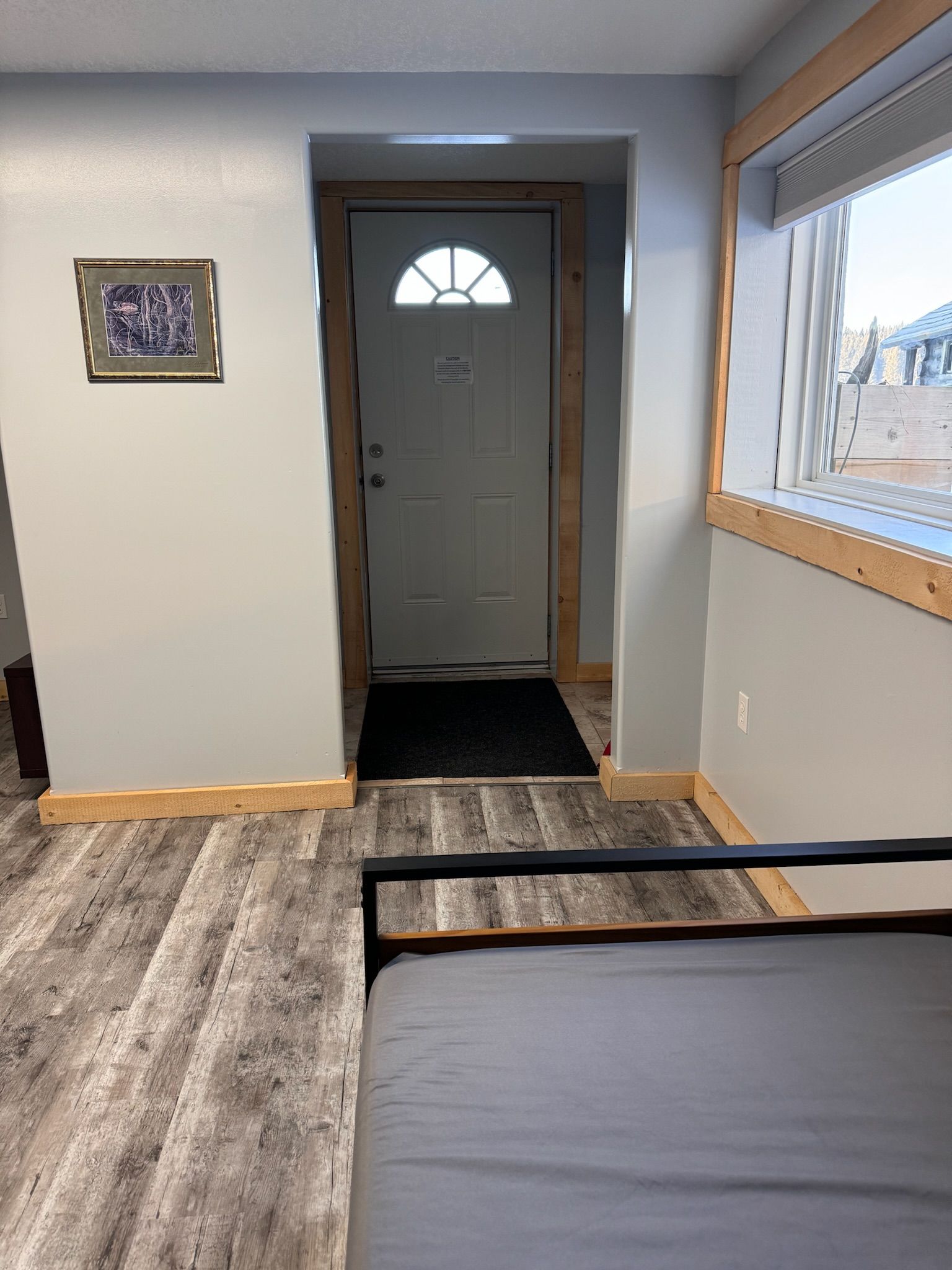 A bedroom with a bed and a doorway leading to the front door