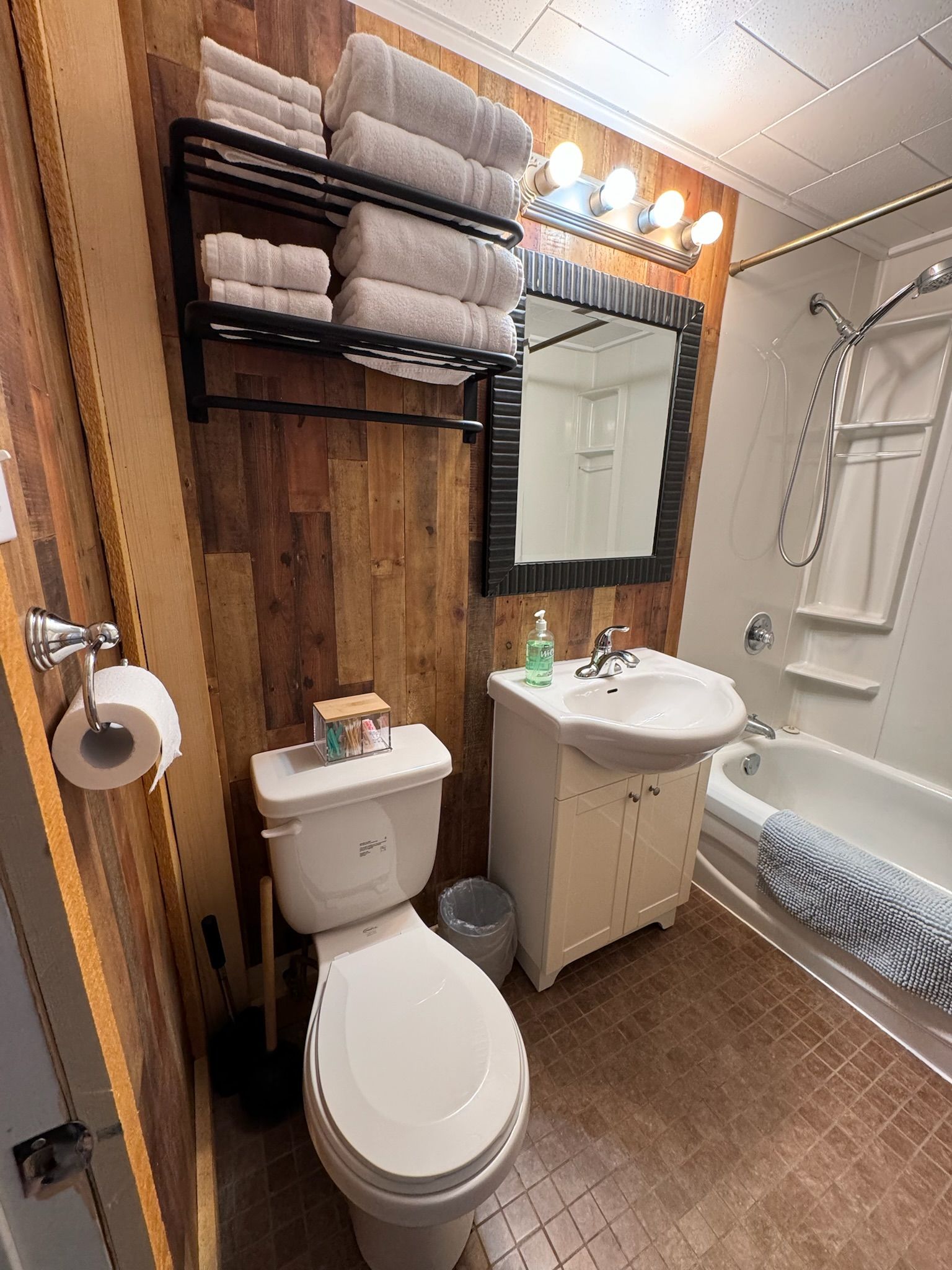 A bathroom with a toilet , sink , mirror and bathtub.