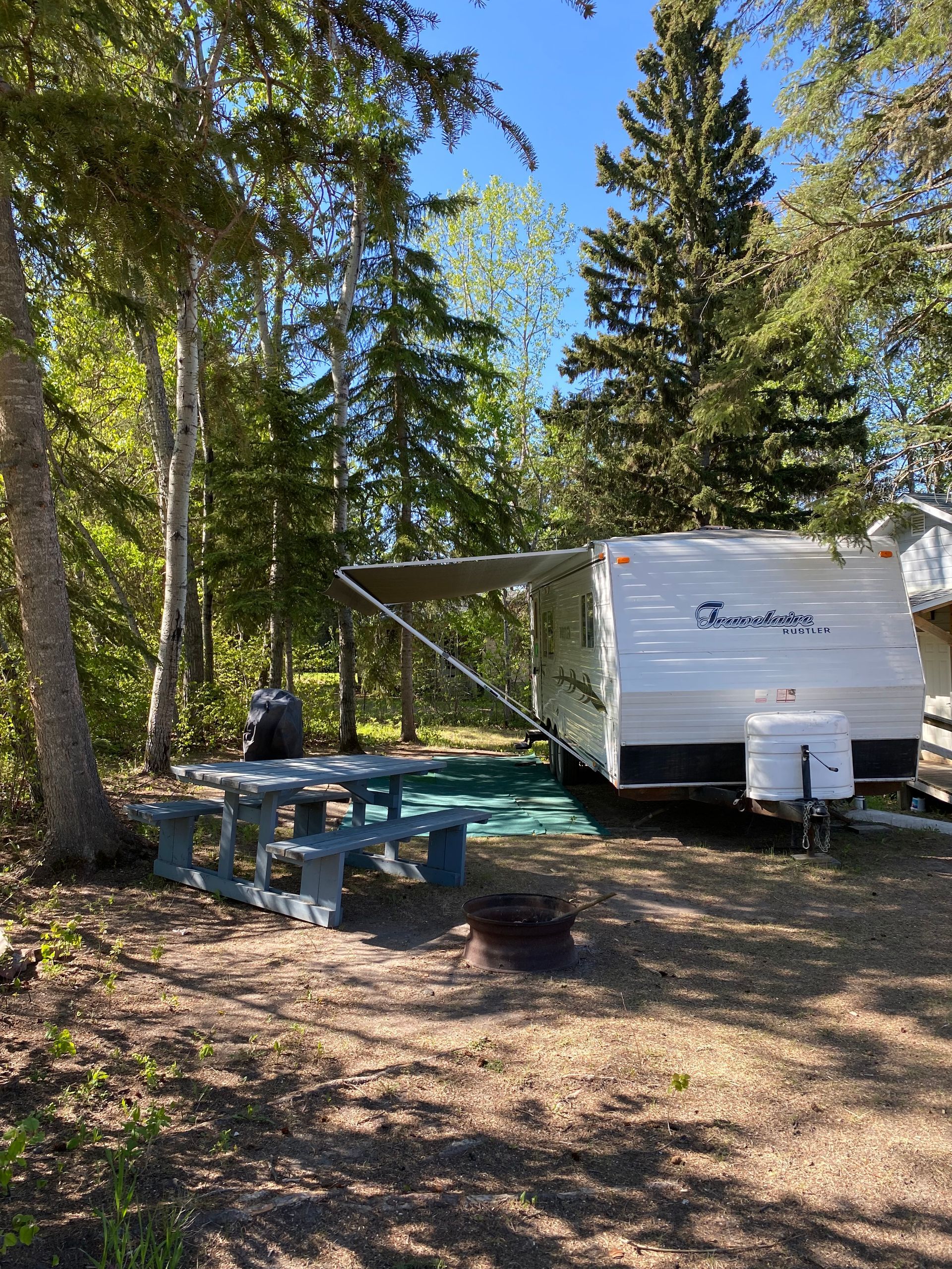 A rv parked in a forest with a picnic table
