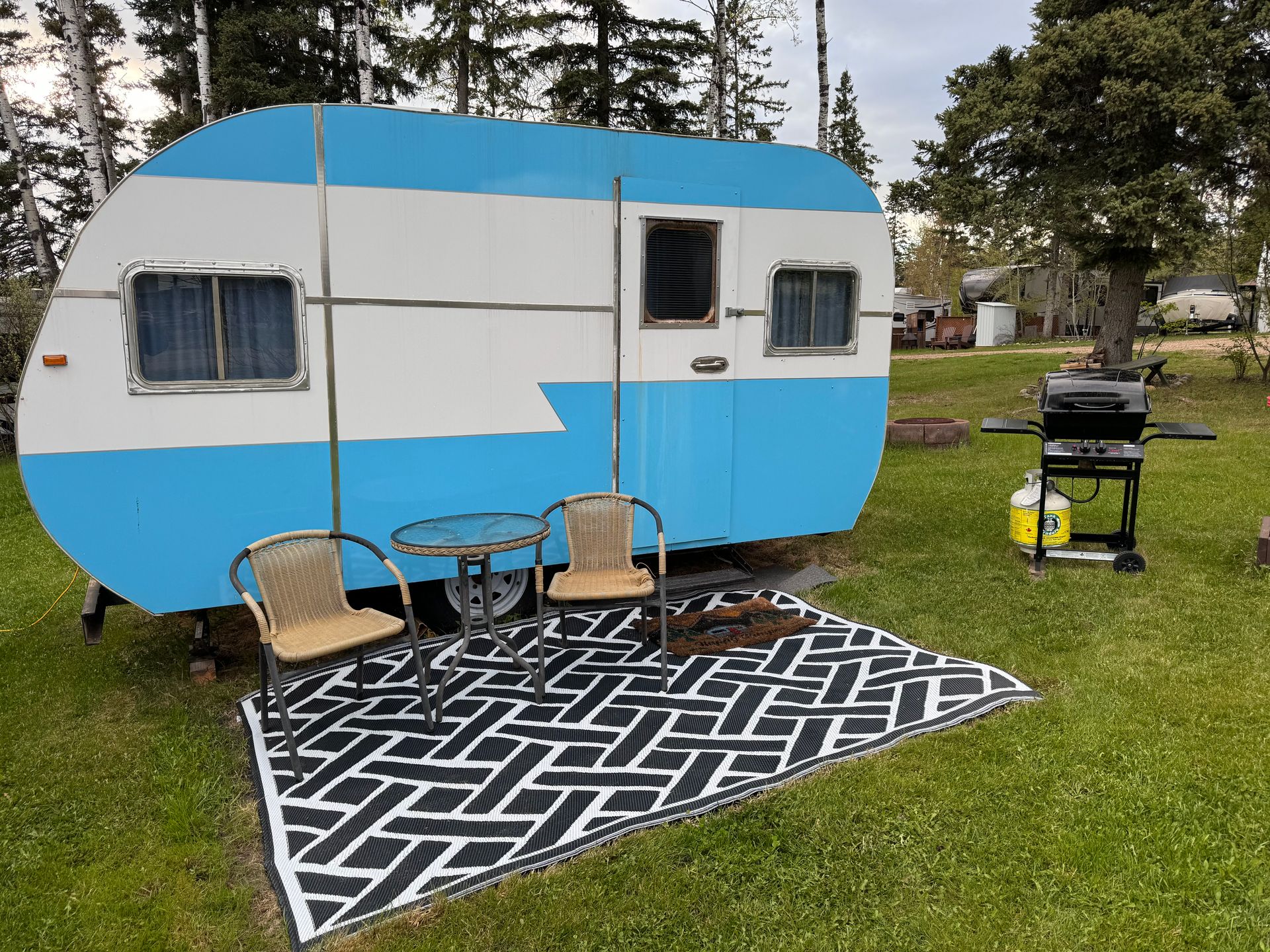 A blue and white trailer is parked in a grassy field.