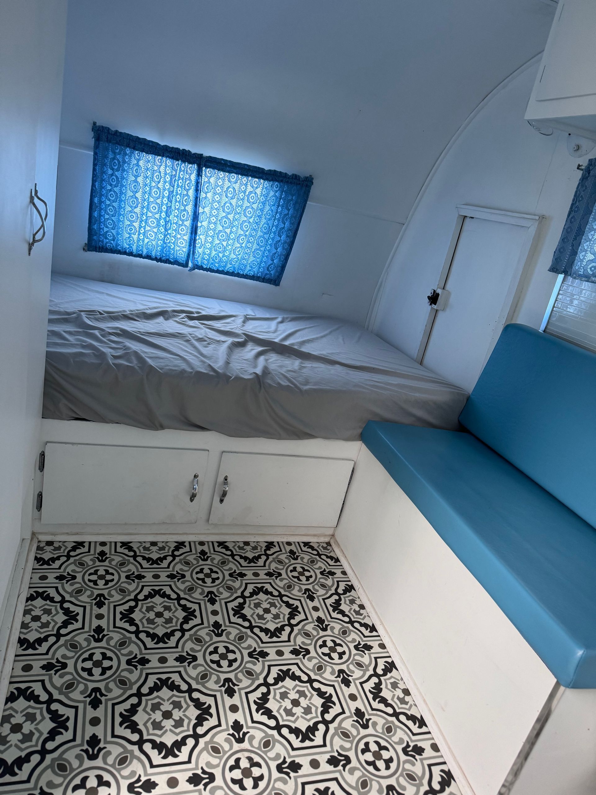 A bedroom in a camper with a bed and a blue couch.