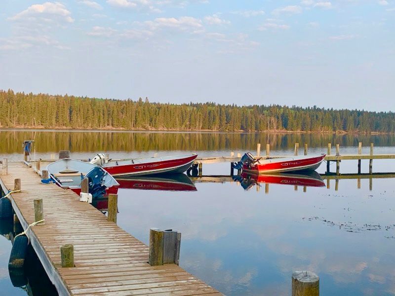 Three boats are docked at a dock on a lake