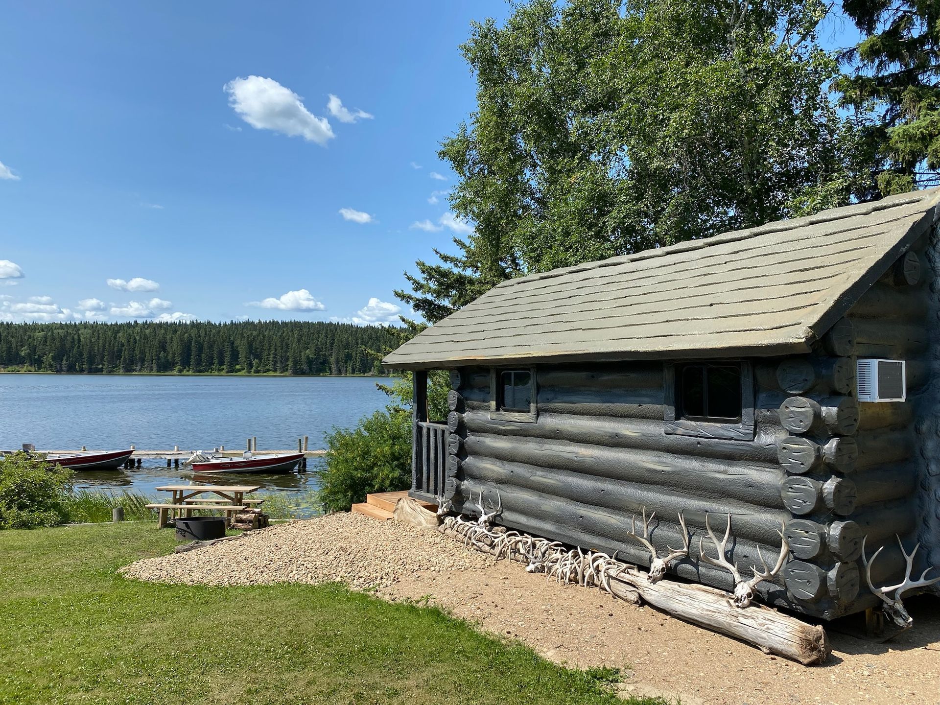 A log cabin is sitting on the shore of a lake.