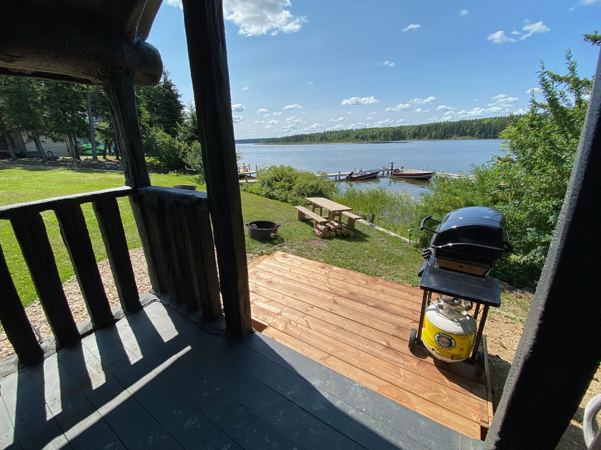 A view of a lake from a porch with a grill on the deck.
