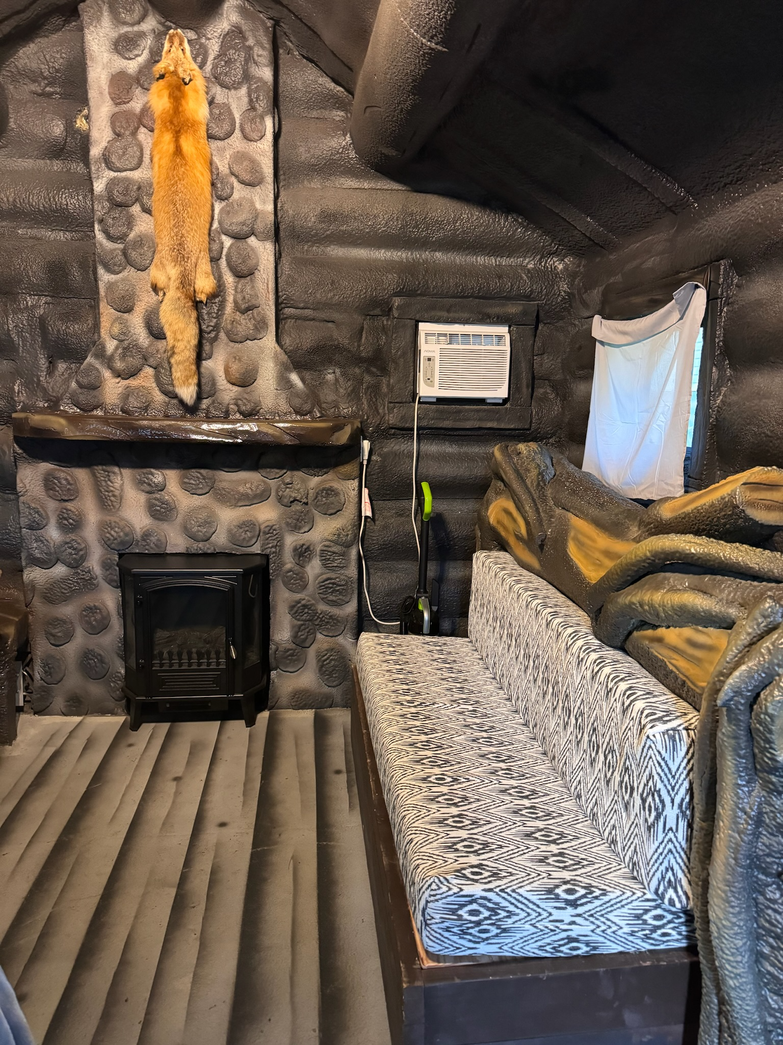 A log cabin with a bed , fireplace , and a cat on the wall.