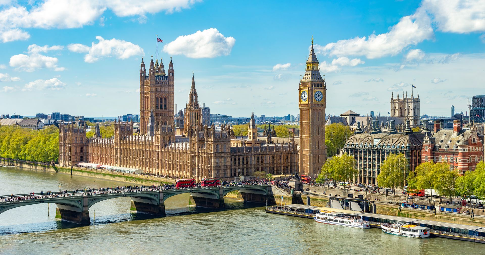 Westminster Palace and Big Ben beside the River Thames under a bright blue sky