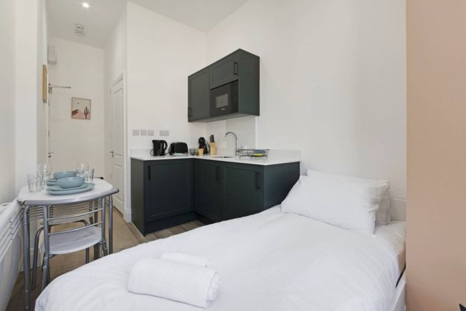 Bright minimalist bedroom with desk, chair, bed, and wardrobe in neutral tones