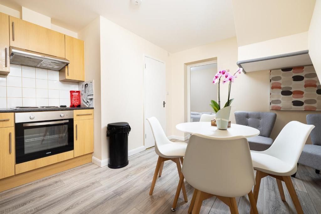 Bright kitchen and dining area with wood cabinets, white table and chairs, and a vase of pink flowers