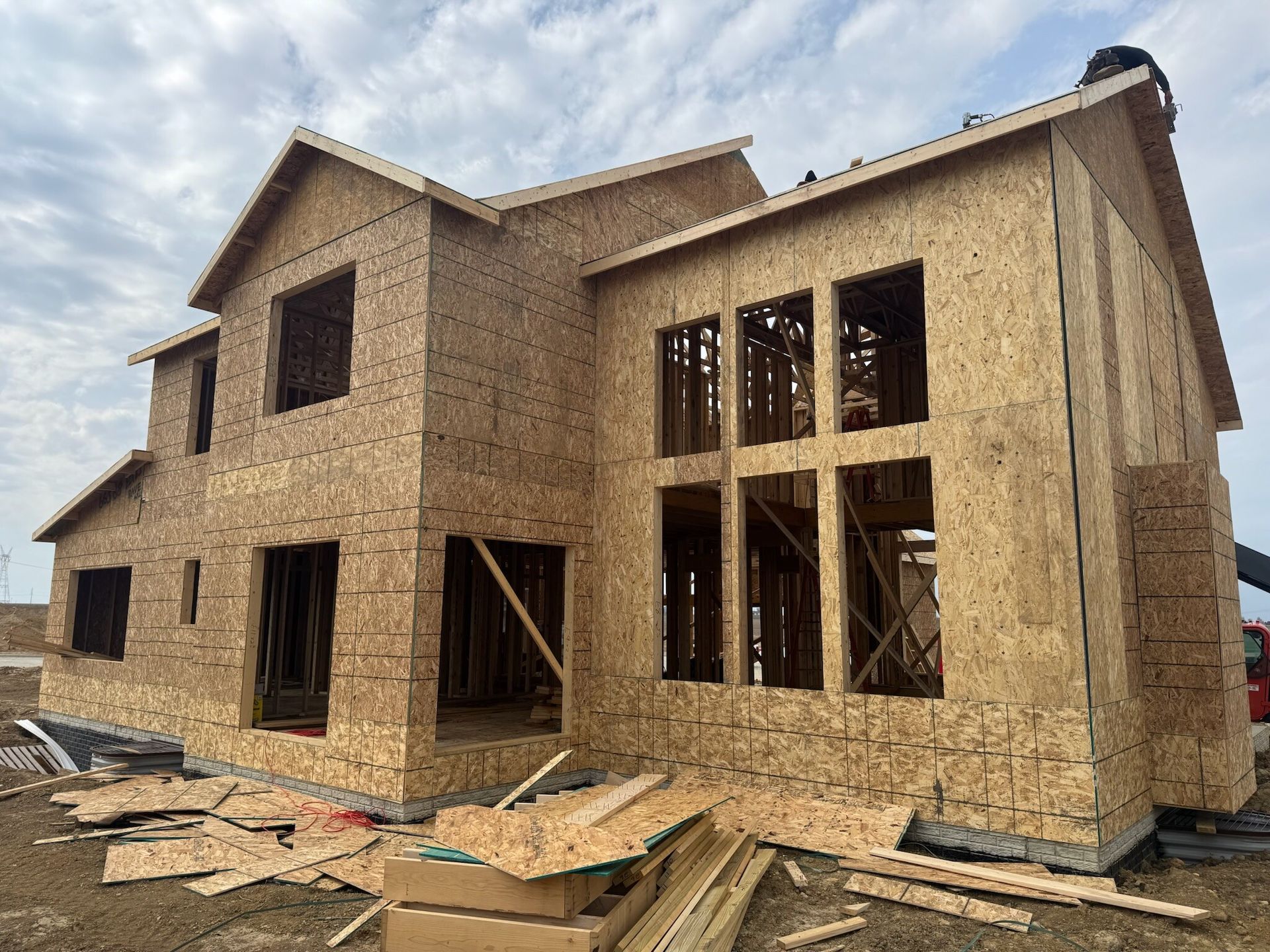 Partially built wooden house under construction with exposed framing and OSB siding