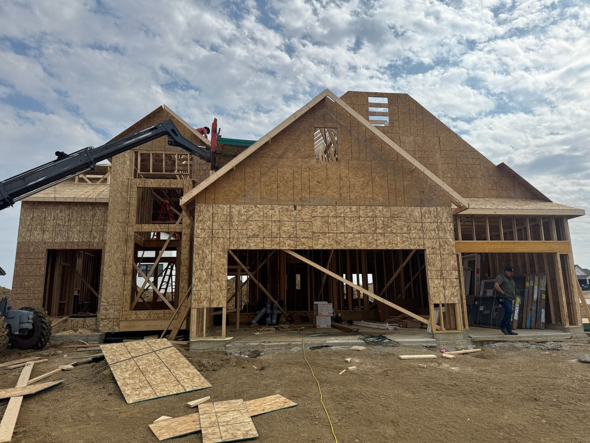 Partially built house with wooden framing and OSB sheathing under a cloudy sky