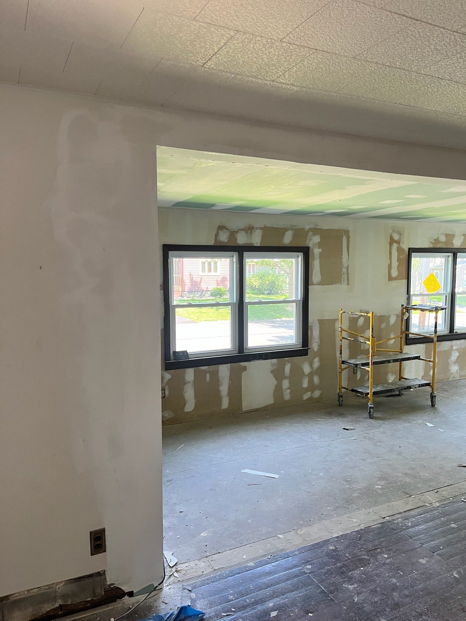 Partially renovated room with open window, bare walls, and a scaffold cart inside