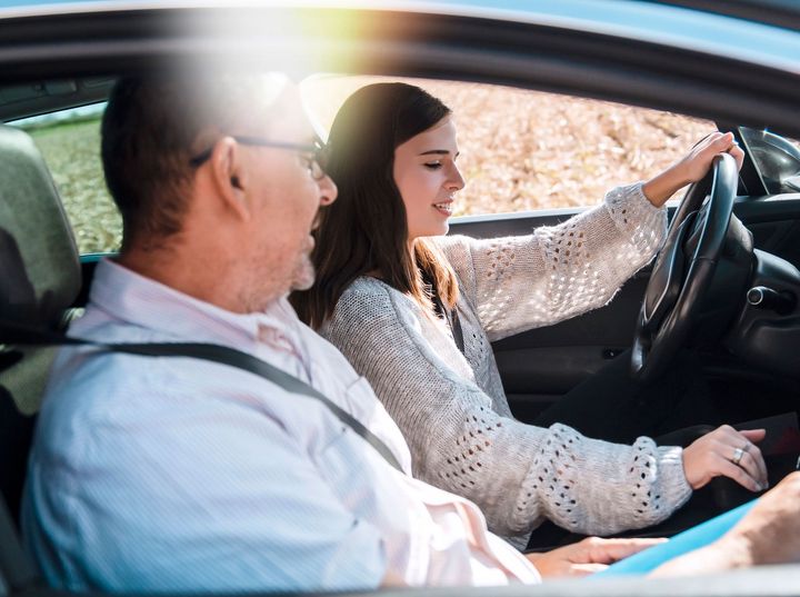 A man is teaching a woman how to drive a car