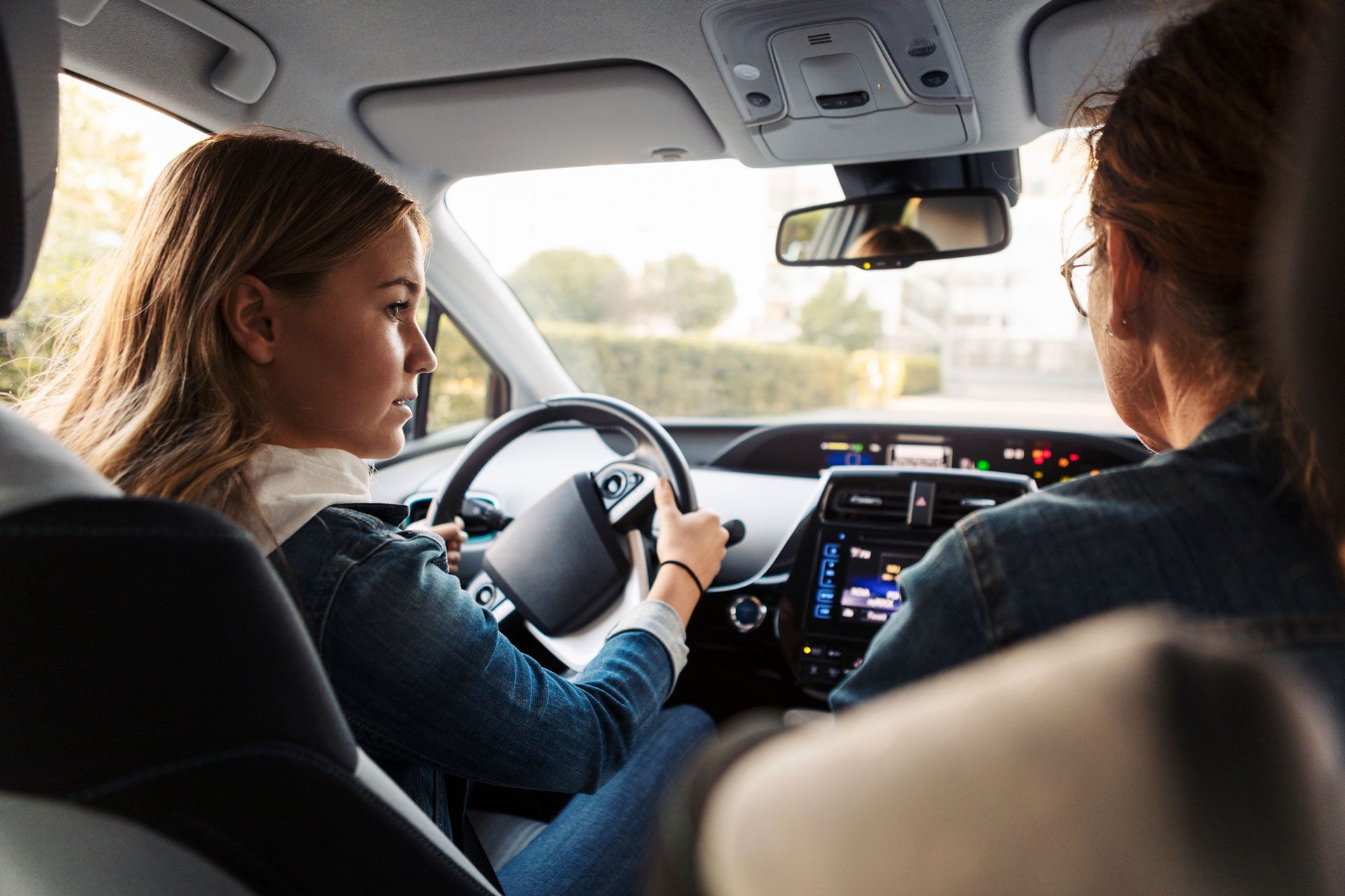 Two women are sitting in a car talking to each other