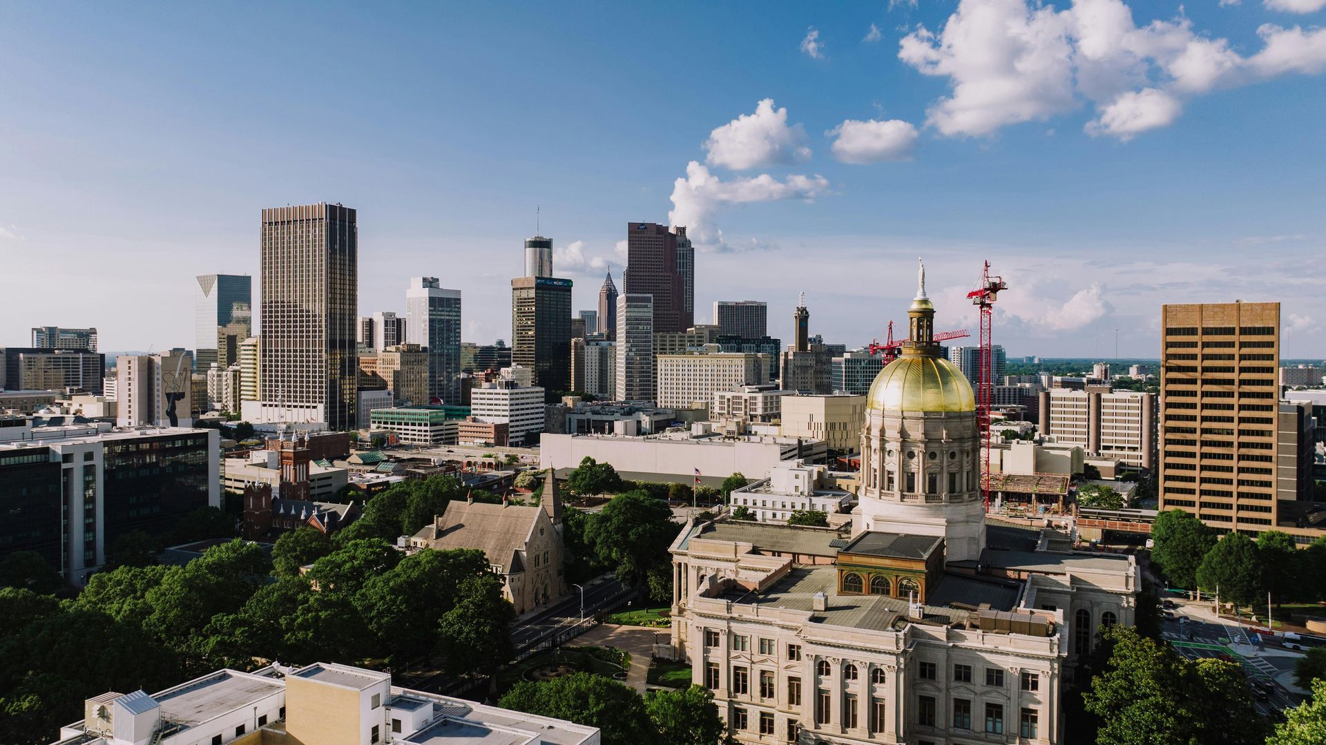 City skyline with a gold-domed capitol building and high-rise towers under a blue sky