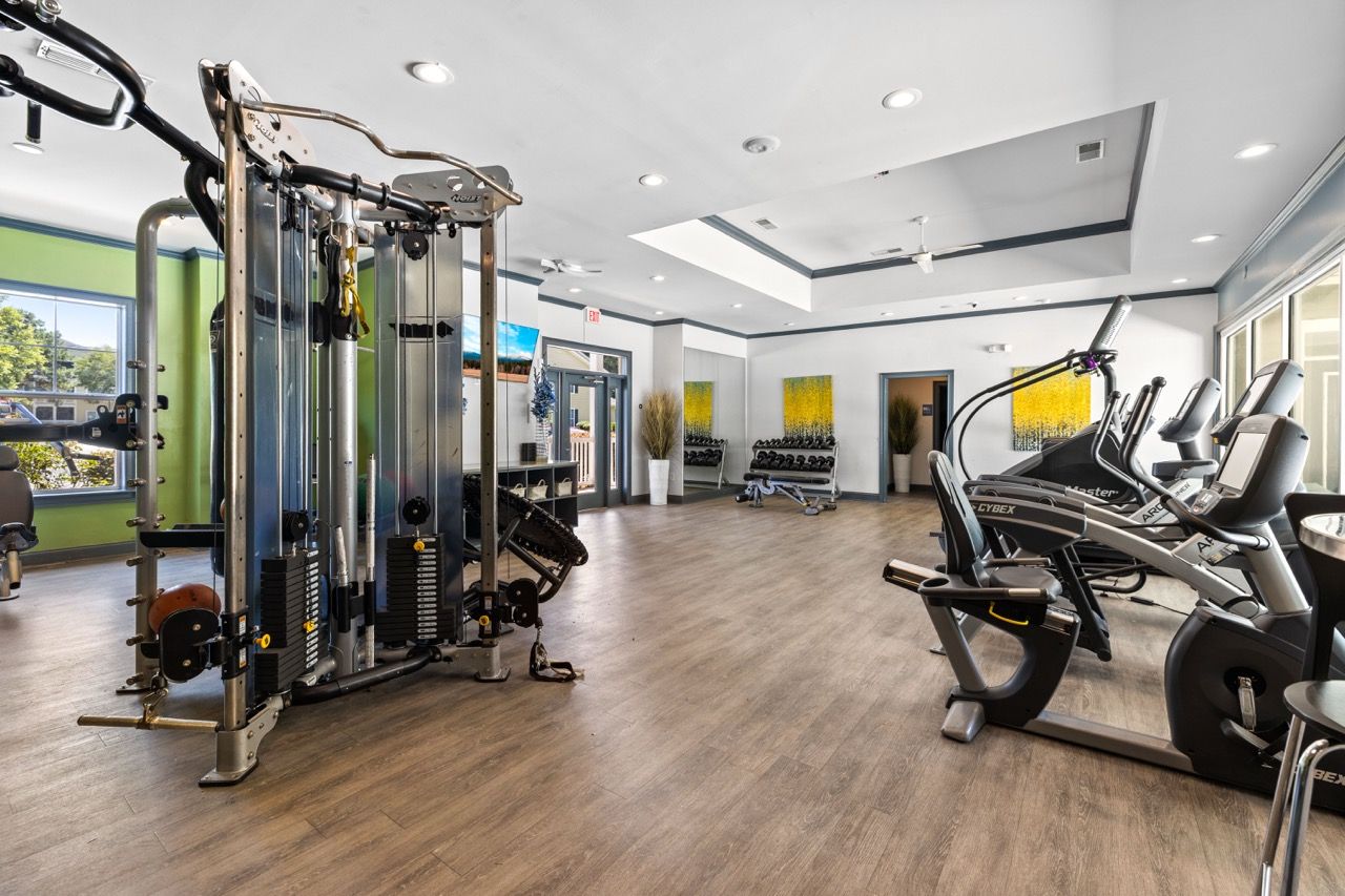 Bright fitness center in a multifamily building with cardio machines and weight machines.