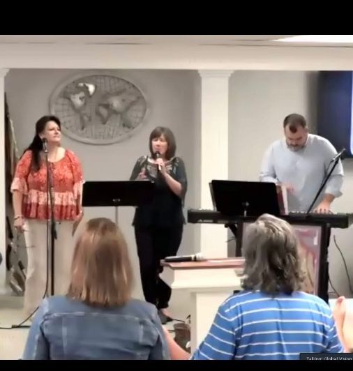 A group of people singing and playing instruments in a room