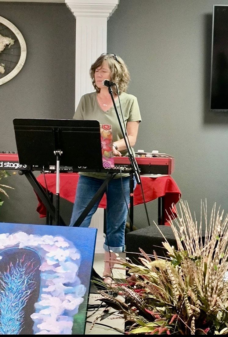 A woman singing into a microphone in front of a keyboard