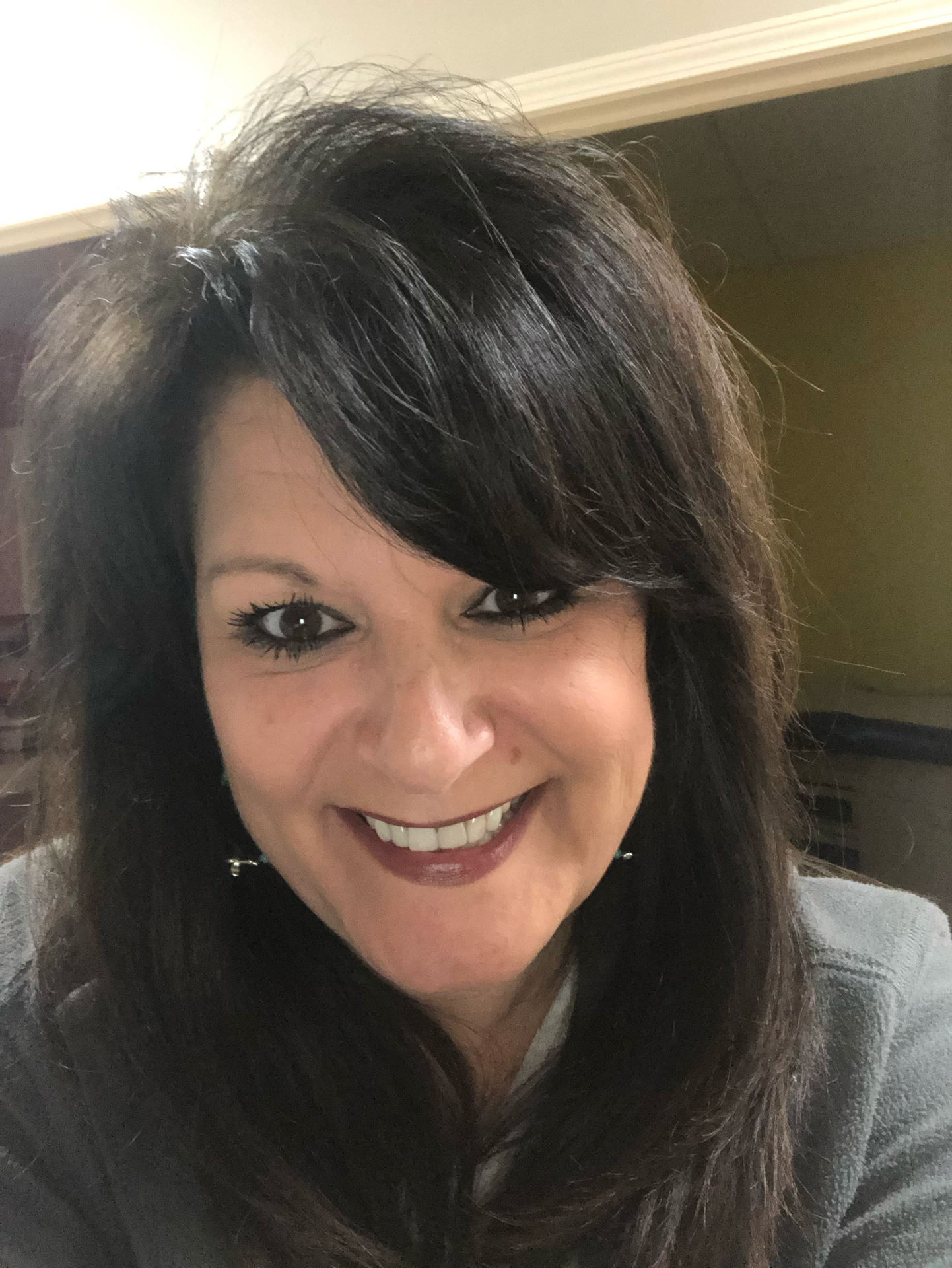 A woman with long dark hair is smiling for the camera