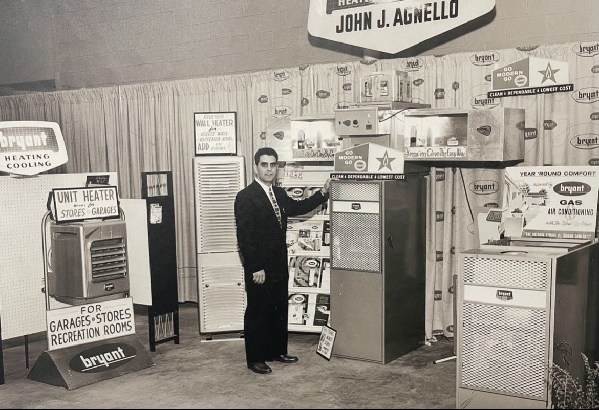 Man in suit at a booth displaying vintage appliances and signs, possibly at a trade show.
