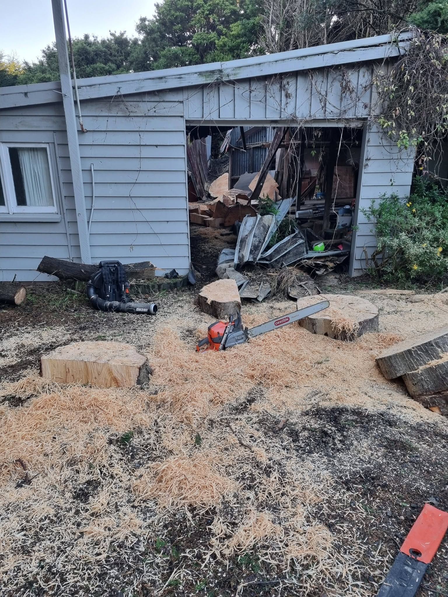 House exterior with blown-out wall and debris scattered across the yard after storm damage