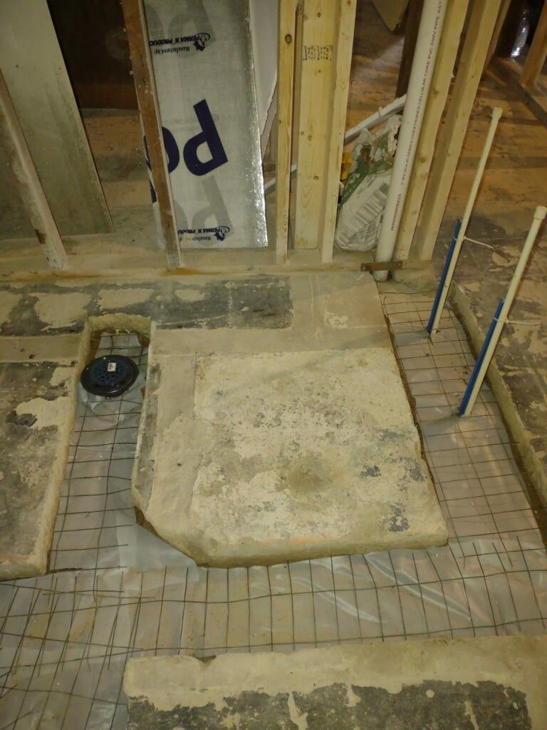 Bathroom under renovation with exposed studs, tile floor, and a removed tub or shower base.