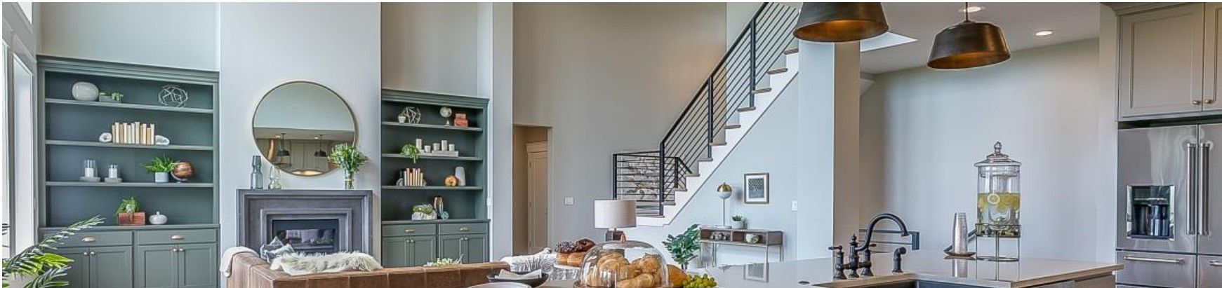 Spacious kitchen with a staircase, fireplace, and green cabinetry. 