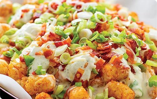 Loaded tater tots with bacon, green onions, and creamy sauce.
