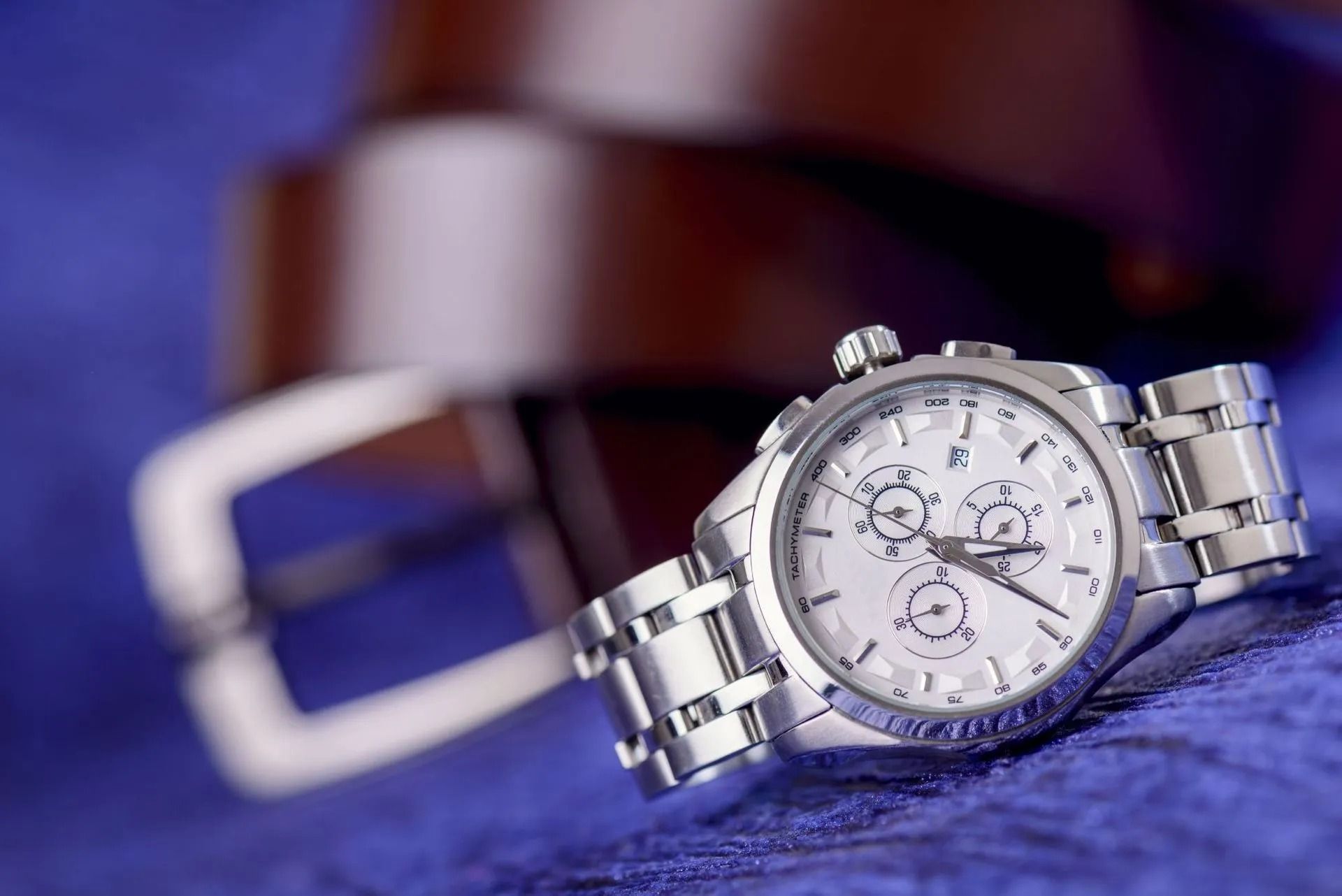 Silver Wristwatch and Brown Leather Belt on a Blue Surface — Coastal Clocks & Watches in Buddina, QLD