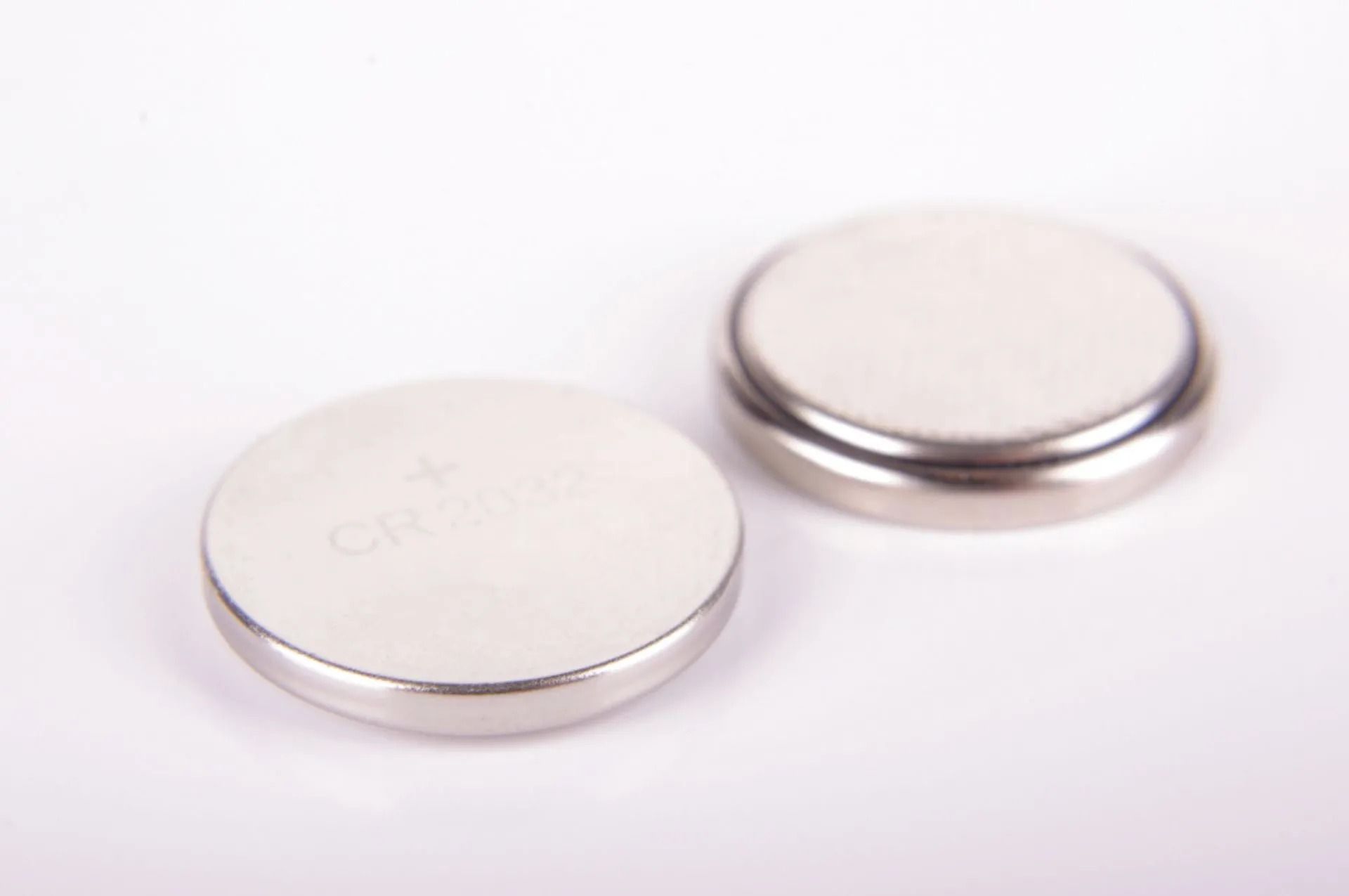 Two Silver and White Button Cell Batteries on a White Surface — Coastal Clocks & Watches in Buddina, QLD