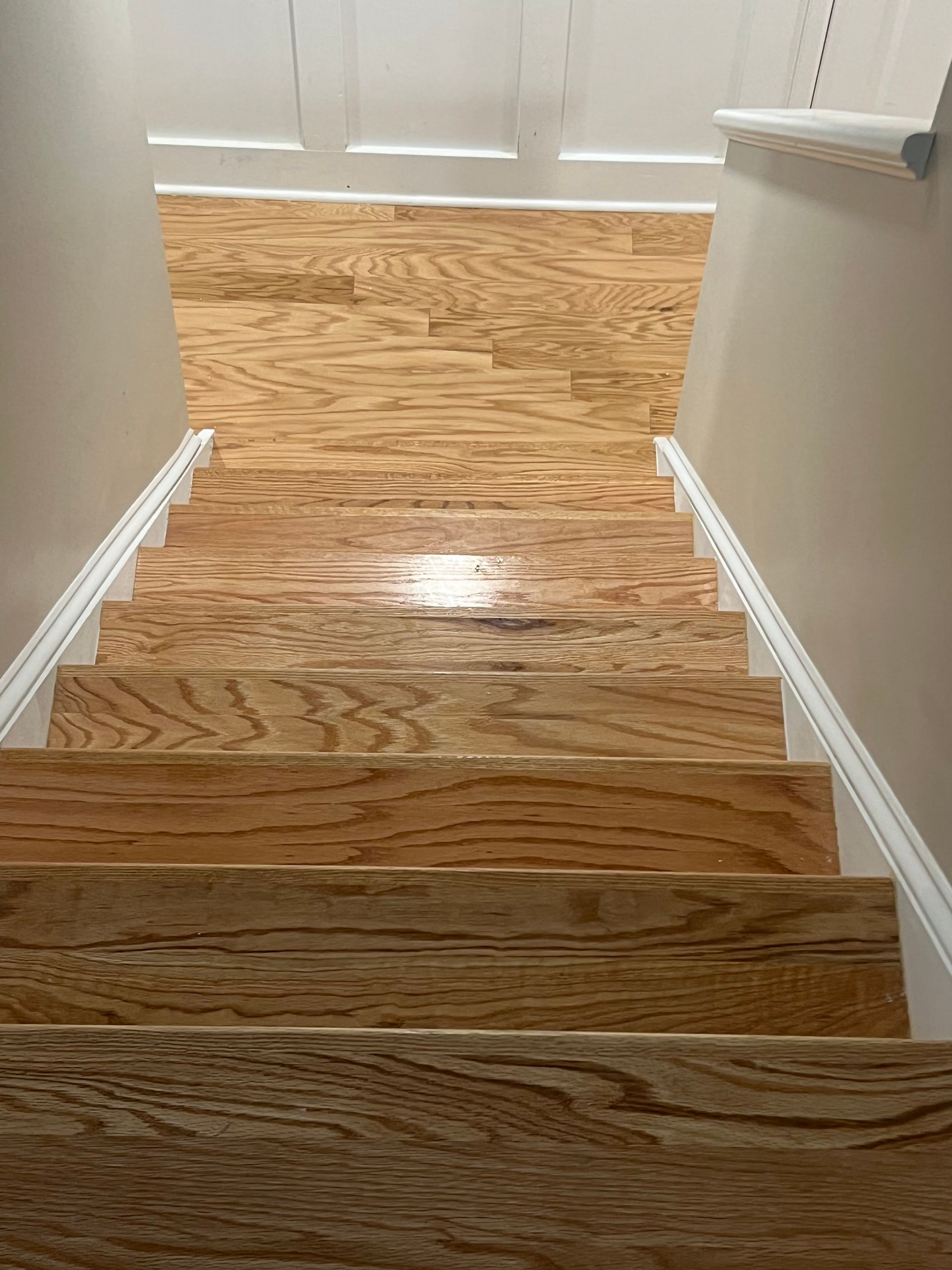 A close up of a wooden staircase in a house with hardwood floors.