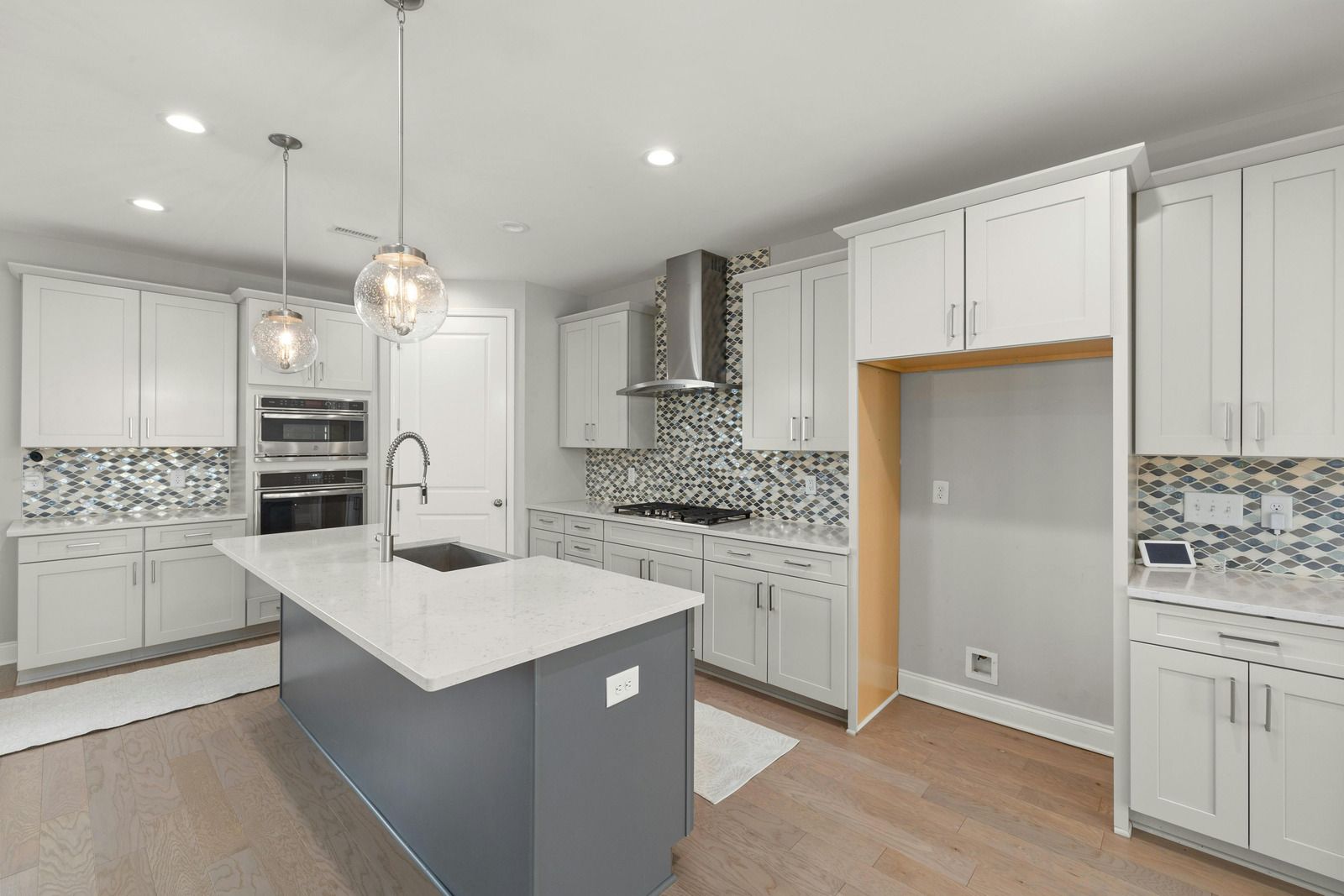 Bright modern kitchen with white cabinets, mosaic backsplash, and a gray island.