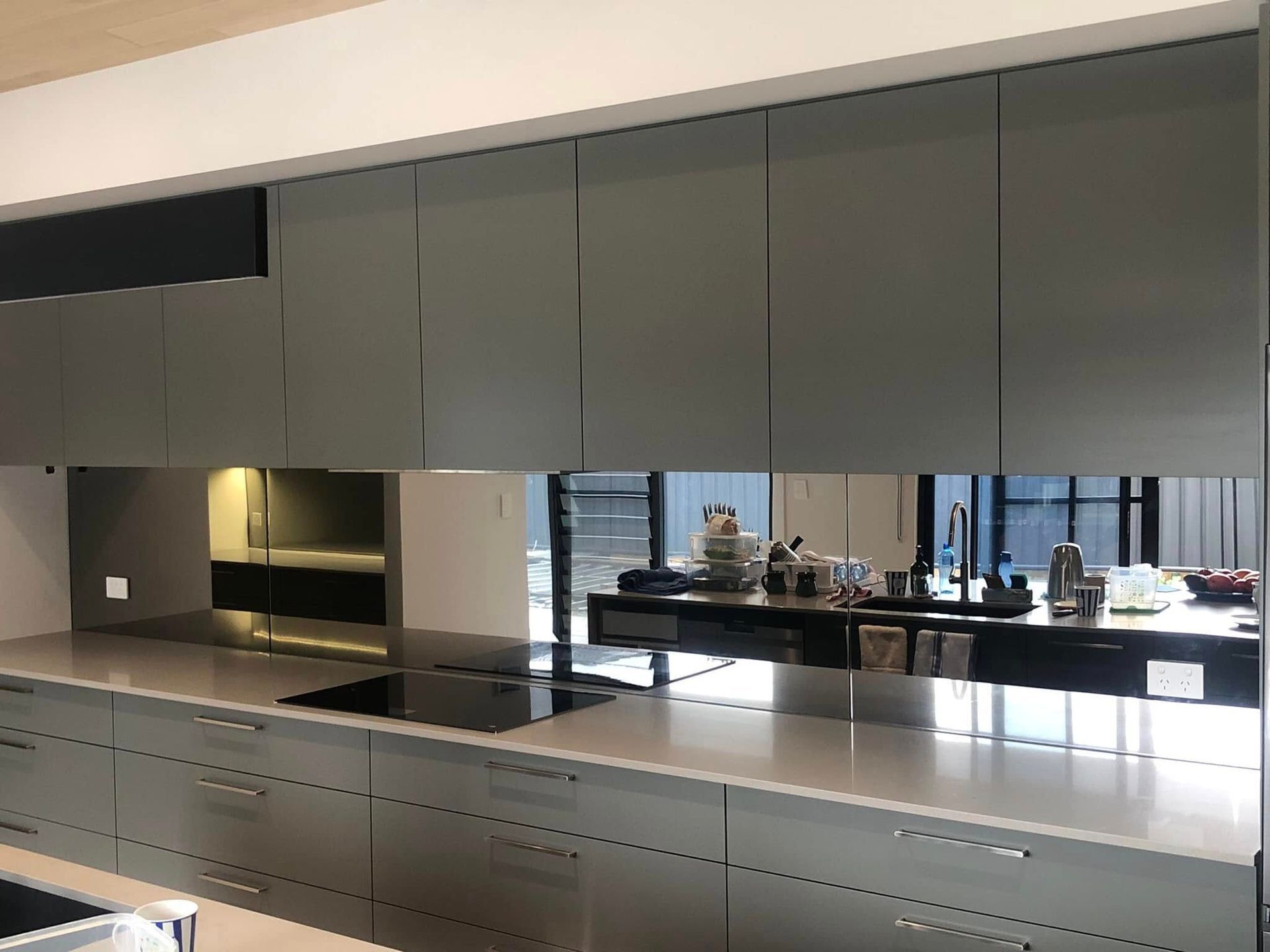 Modern Kitchen With Gray Cabinets Mirrored Backsplash Reflecting the Room — Long Jetty Glass in The Entrance, NSW