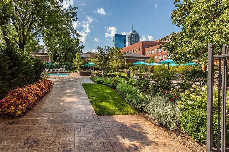 A walkway leading to a pool in a park with a city in the background.