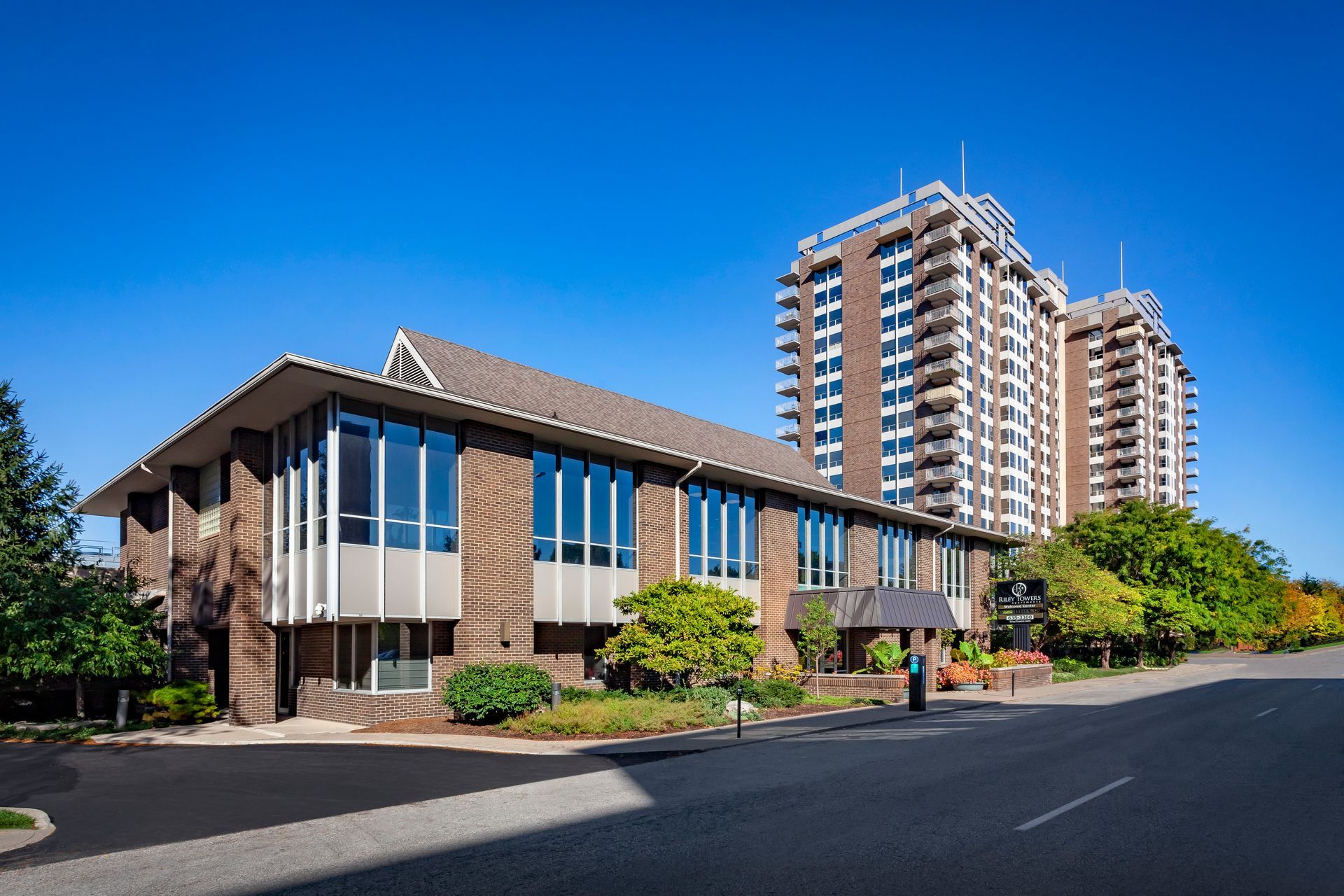 A large brick building with a lot of windows is next to a tall building at  Riley Towers, Indianapolis, IN. 