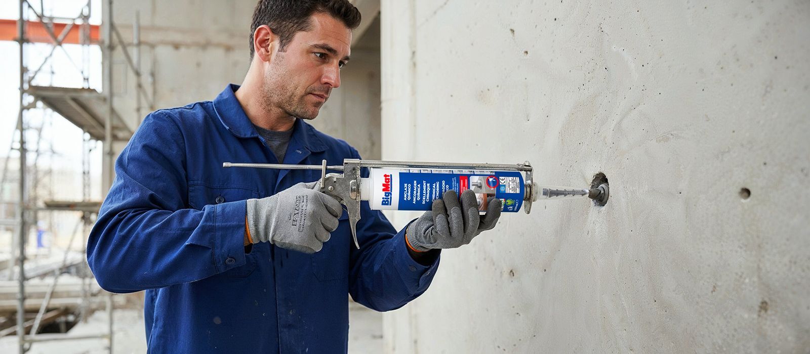 Ouvrier en combinaison bleue utilisant un pistolet pour injecter du mortier dans un mur en béton