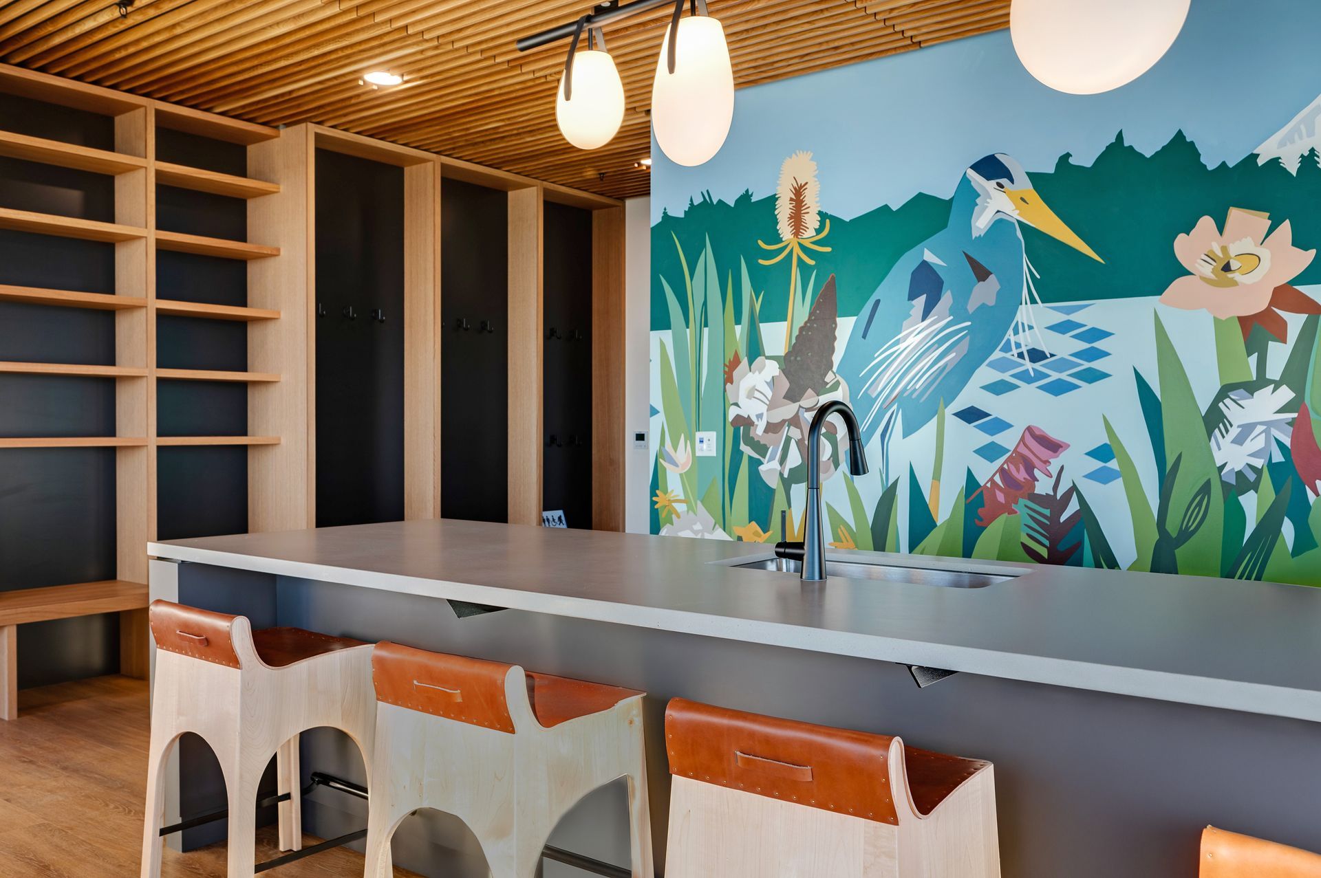 Kitchen area with a mural, countertop, stools, and bookshelves.