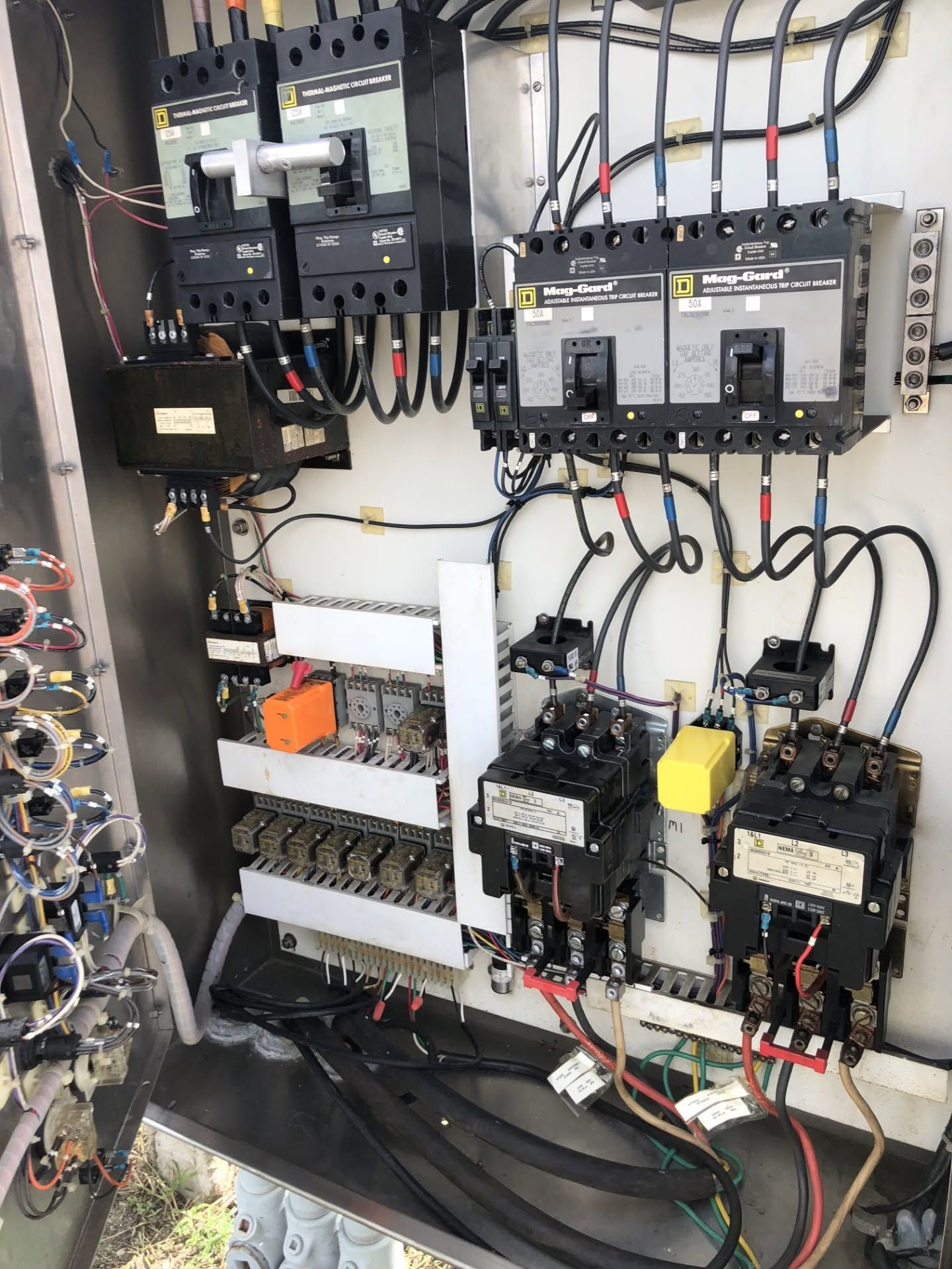 Electrical control panel with circuit breakers, relays, and wired components inside a metal enclosure