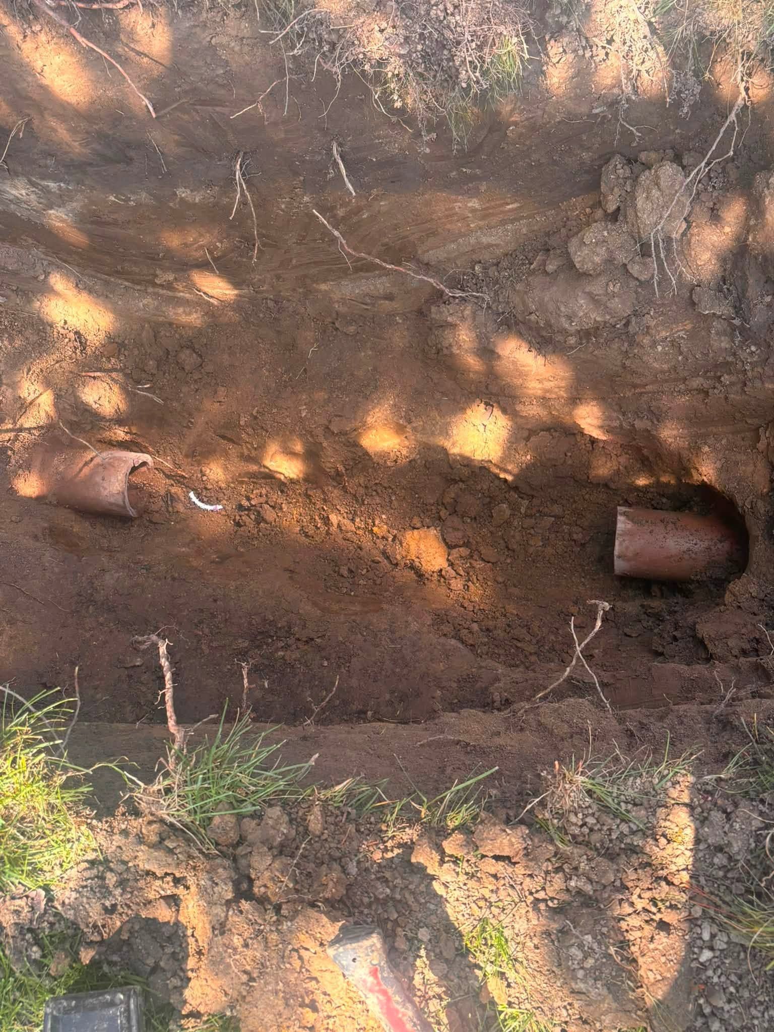 Dirt excavation wall with a small rusted metal cylinder embedded on the right and scattered leaves above.