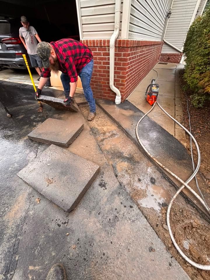 Two workers shoveling wet dirt beside a brick house during cleanup work