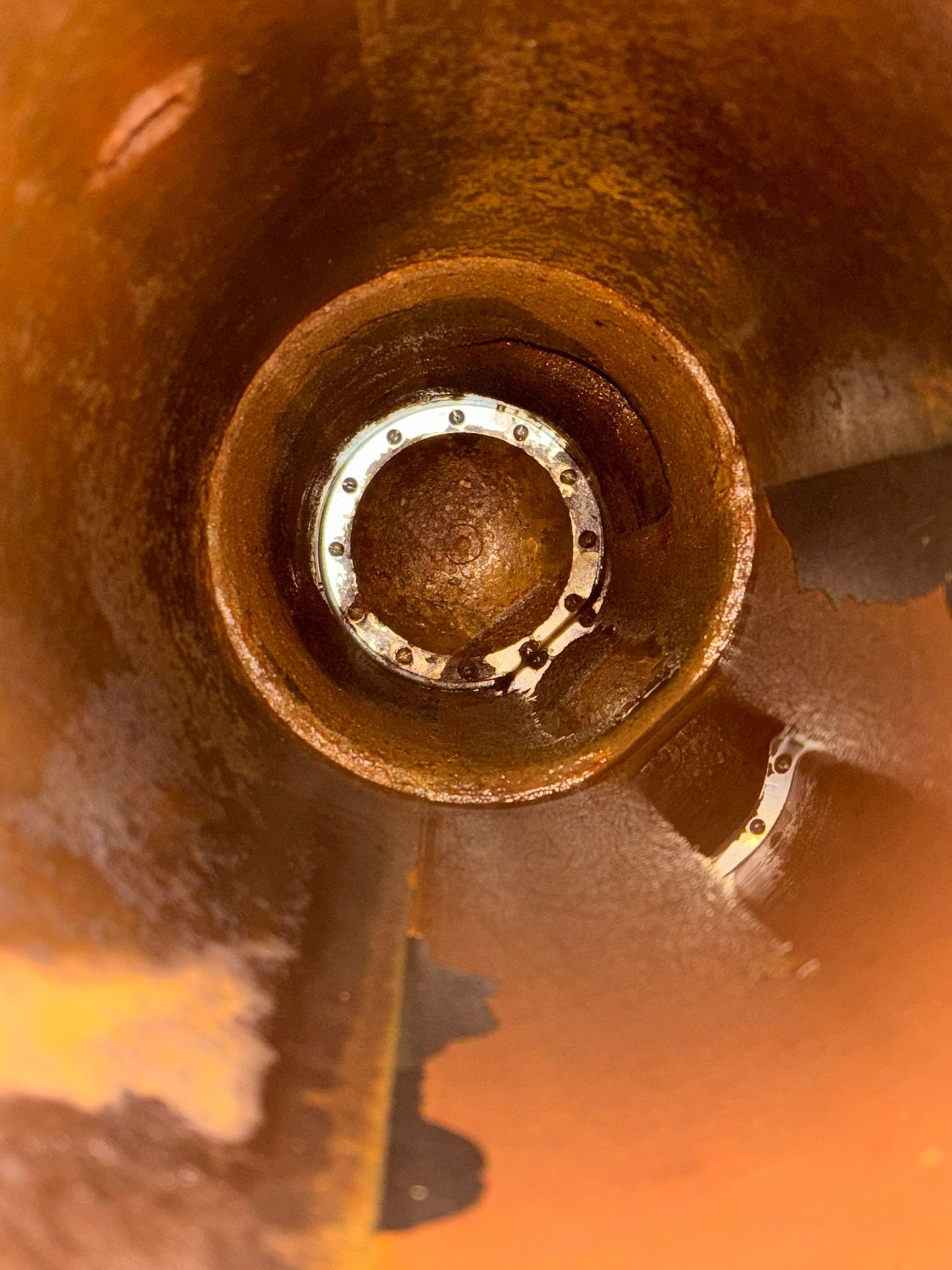 Close-up of a brown metal bowl or cup with a circular white ring inside and warm orange reflections