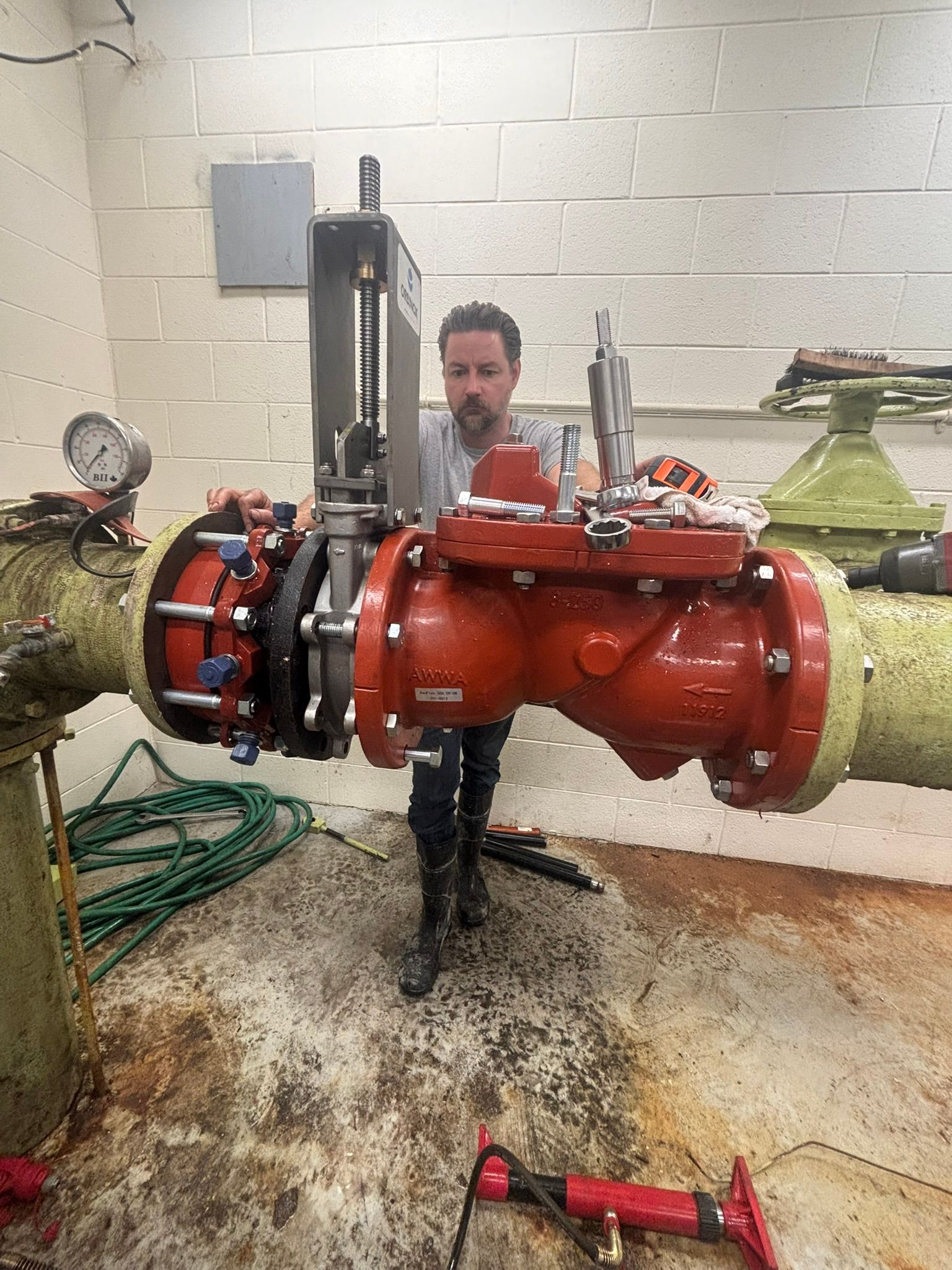 Person standing behind a large red industrial pipe assembly in a utility room