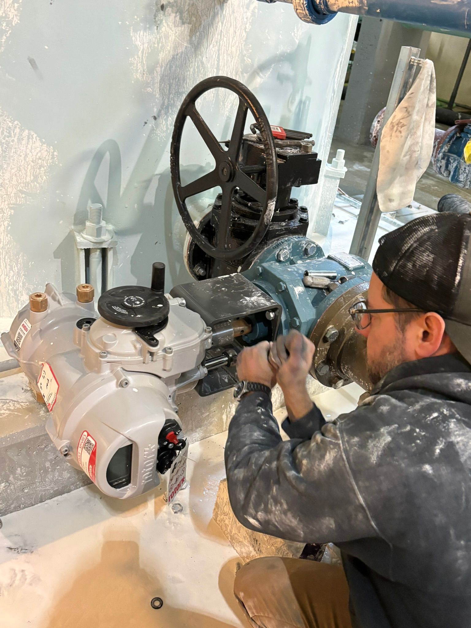 Technician working on a large industrial machine with a handwheel in a workshop setting