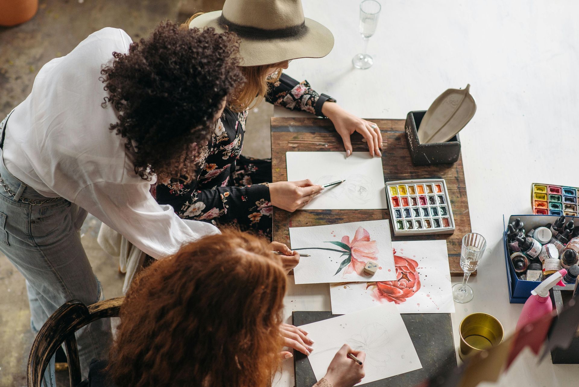 A group of purpose-driven women co-creating at a table painting with watercolors.