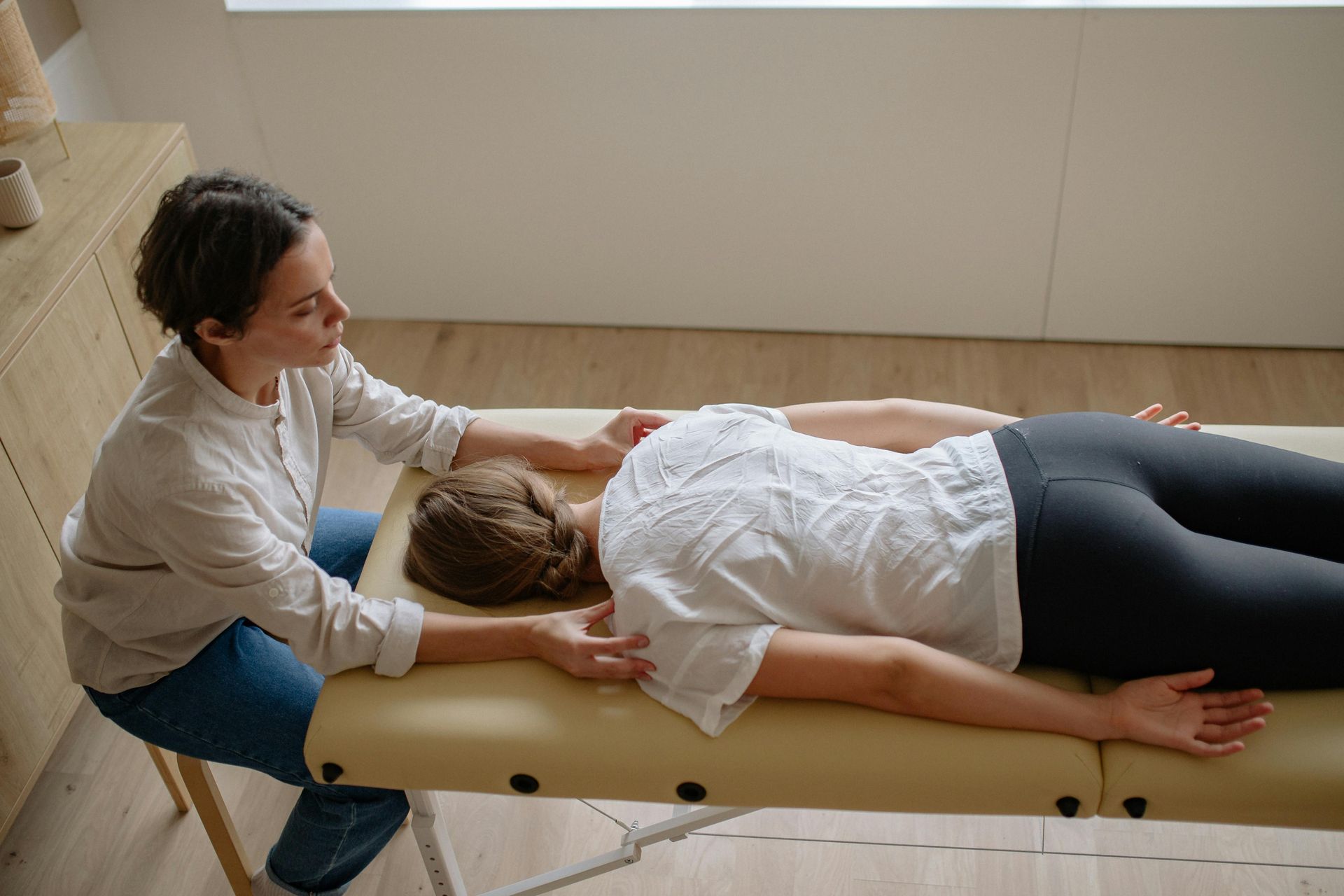 A healthcare worker supports a person's arm, assessing their elbow's mobility.