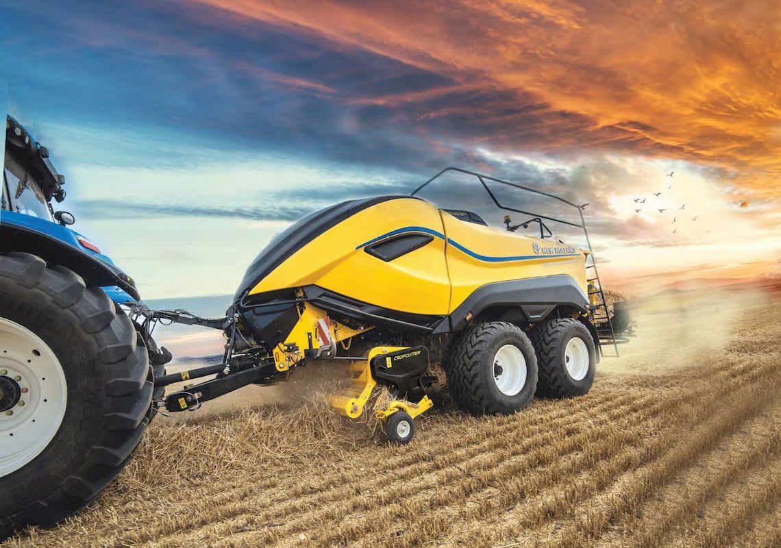 A Yellow and Black Tractor Is Pulling a Yellow and Black Baler in A Field — Cheshire Machinery in Murgon, QLD